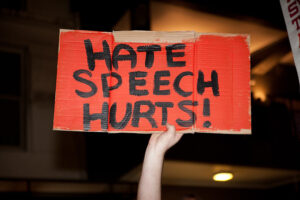 Person holding cardboard with the text ''hate speech hurts!''